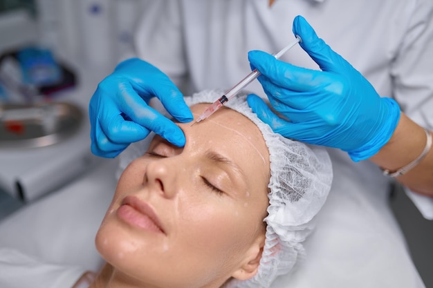 anti aging treatment filler injection into eyebrow side view cosmetologist putting puncture patient skin 266732 32064 1